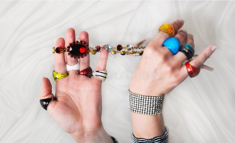Mains du ` s de femme avec beaucoup d'anneaux en verre colorés, bracelet et nekla photo libre de droits Mains du ` s de femme avec beaucoup d'anneaux en verre colorés, bracelet et nekla photo libre de droits