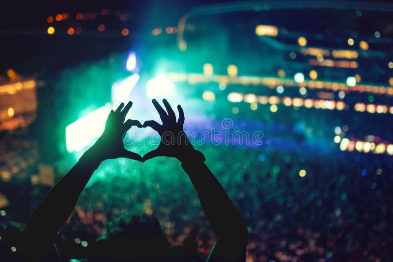 Mains en forme de coeur au concert, aimant l'artiste et le festival Concert de musique avec les lumières et la silhouette d'appré