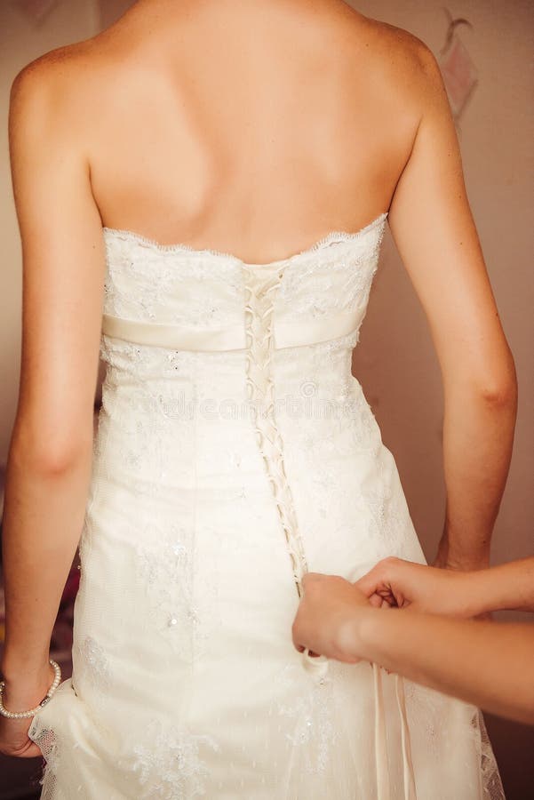 Mains femelles attachant des boutons sur une robe de mariage photos stock Mains femelles attachant des boutons sur une robe de mariage photos stock