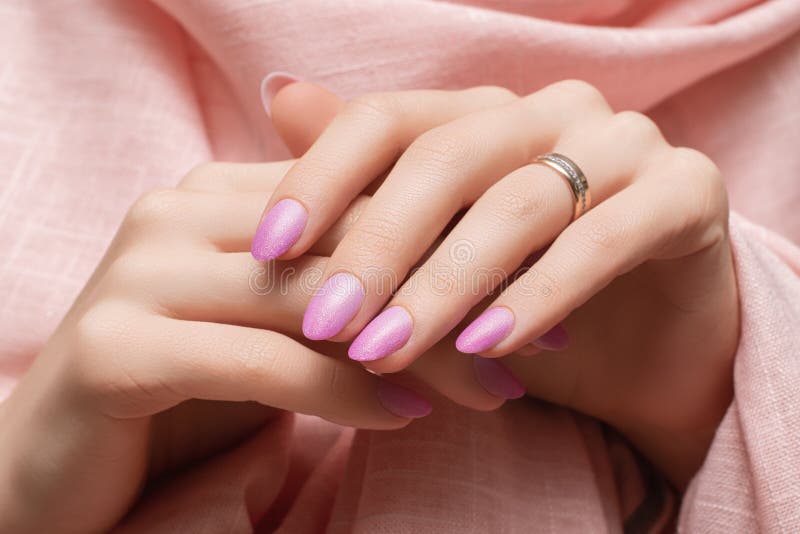 Mains femelles avec la conception de l'ongle rose. Manucure rose de vernis à ongles scintillatrice. Mains de femme sur le tissu ro