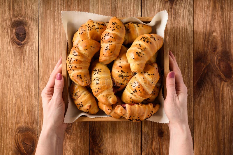 Mains femelles tenant le plateau avec les petits pains doux de pain photographie stock Mains femelles tenant le plateau avec les petits pains doux de pain photographie stock