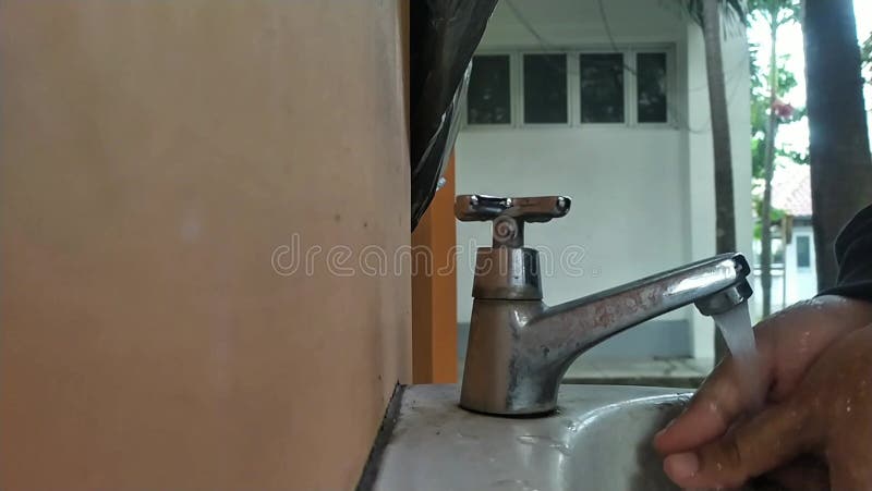 Mains lavées sous l'eau courante dans un lavabo extérieur. banque de vidéos