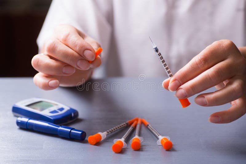 Mains patientes femelles tenant la seringue ouverte d'insuline, glucometer sur la table images libres de droits Mains patientes femelles tenant la seringue ouverte d'insuline, glucometer sur la table images libres de droits