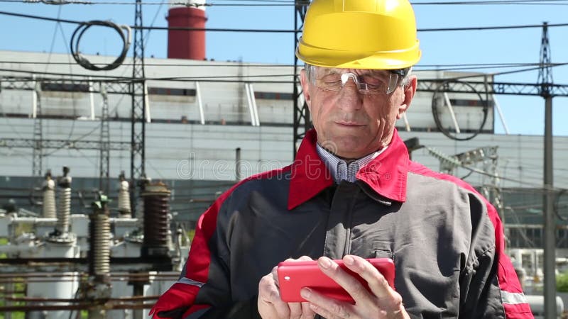 Maintenance worker with red smartphone at power station