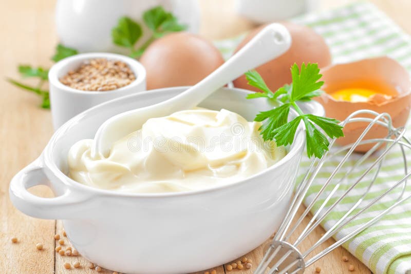 Mayonnaise in a bowl with ingredients on a wooden table. Mayonnaise in a bowl with ingredients on a wooden table