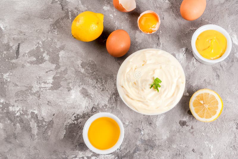 Mayonnaise with ingredients for cooking - eggs, vegetable oil, mustard, lemon, parsley. On the grey stone concrete table top view copy space. Mayonnaise with ingredients for cooking - eggs, vegetable oil, mustard, lemon, parsley. On the grey stone concrete table top view copy space