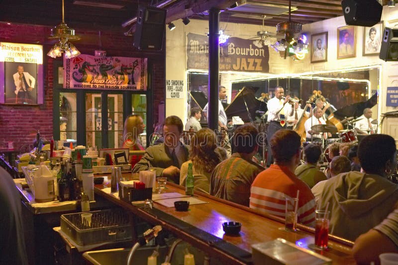 Maison Bourbon Jazz Club with Dixieland band and trumpet player performing at night behind bar with drinking customers in French Quarter in New Orleans, Louisiana. Maison Bourbon Jazz Club with Dixieland band and trumpet player performing at night behind bar with drinking customers in French Quarter in New Orleans, Louisiana