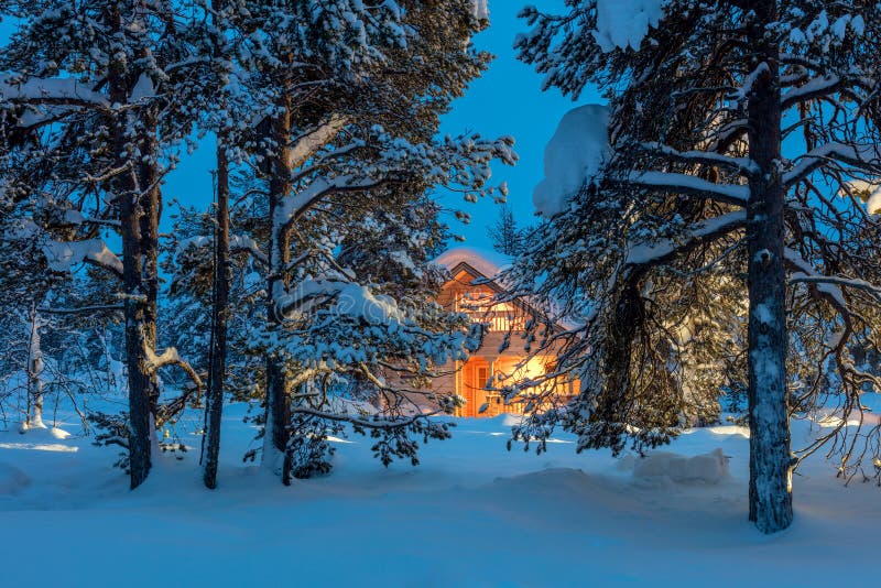 Maison chaude dans la forêt neigeuse d'hiver de nuit images stock Maison chaude dans la forêt neigeuse d'hiver de nuit images stock