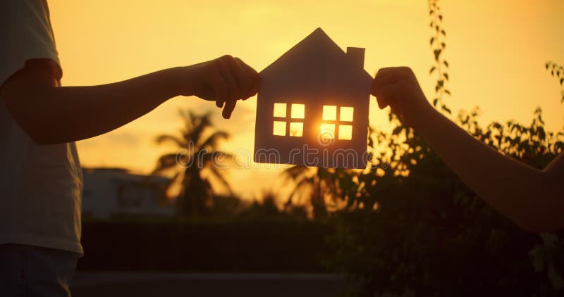 Maison d'achat Dream. Papier maison mains famille soleil brille dans la fenêtre closeup. Maison de papier à main au coucher du sol clips vidéos