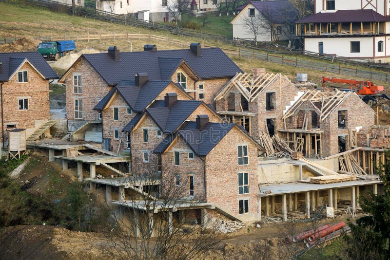 Maison non finie spacieuse de nouvelle grande brique, condominium de manoir avec le toit décalé brun en construction Solution arc photographie stock Maison non finie spacieuse de nouvelle grande brique, condominium de manoir avec le toit décalé brun en construction Solution arc photographie stock