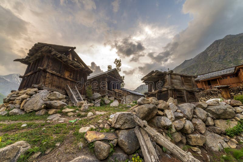 Maison traditionnelle en bois avec le mur de roche pendant le coucher du soleil au dessus de montagne photographie stock Maison traditionnelle en bois avec le mur de roche pendant le coucher du soleil au dessus de montagne photographie stock