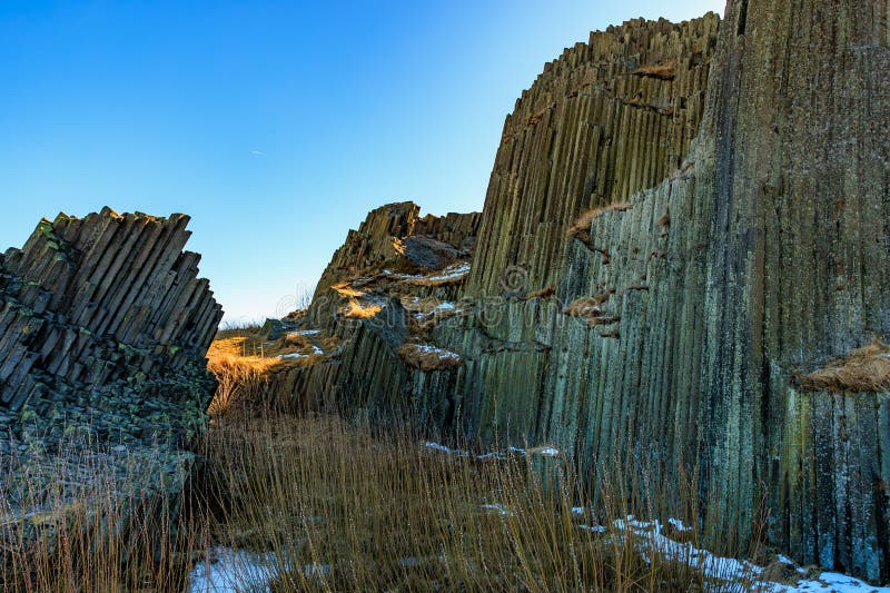 Majestic basalt columns under clear blue sky in natural landscape stock images