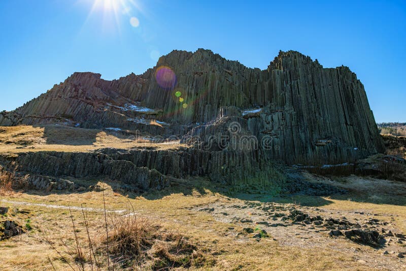 Majestic basalt rock formation under clear blue sky with sunlight royalty free stock image