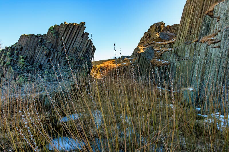 Majestic basalt rock formations with grass in sunlight stock photo