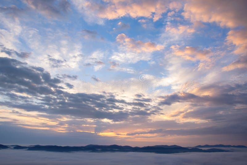 Majestic clouds illuminated by sunrise over mountains