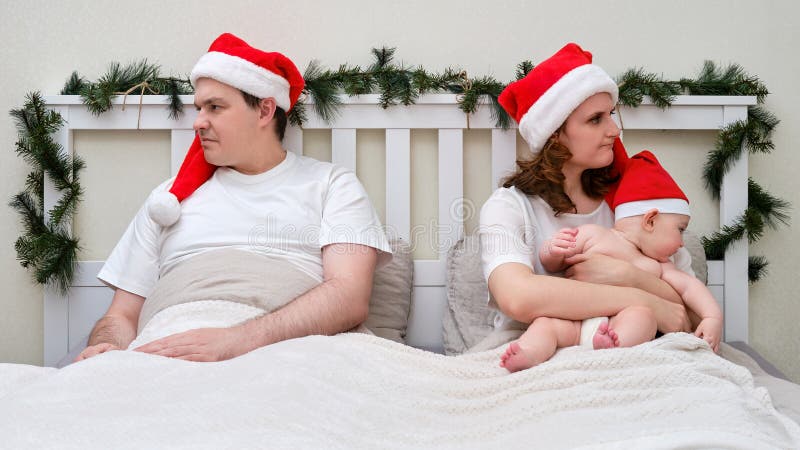 Maka och hustru med barn i sängen som dekorerats för julklapp arkivfoton