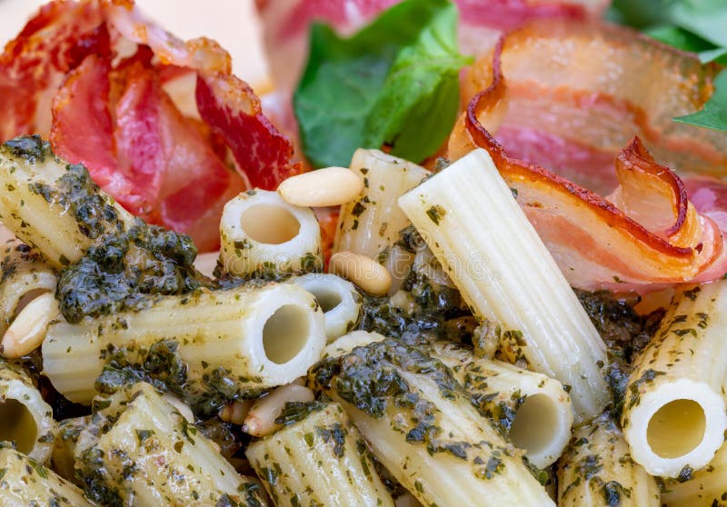 Makaroni med pestopennerigate Med löken och bacon sörjer ost, basilika, muttrar, vitlök arkivbild Makaroni med pestopennerigate Med löken och bacon sörjer ost, basilika, muttrar, vitlök arkivbild