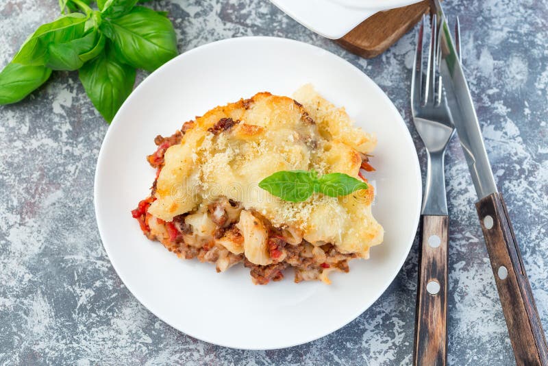 Makaronieldfast form med jordnötkött, ost och tomaten på den vita plattan, horisontal bästa sikt royaltyfri fotografi Makaronieldfast form med jordnötkött, ost och tomaten på den vita plattan, horisontal bästa sikt royaltyfri fotografi