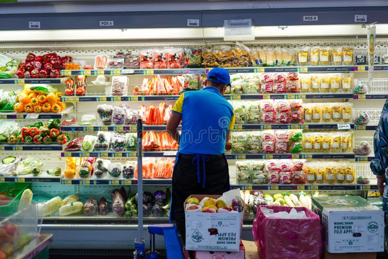 Makassar, October 30, 2022: Salesman working at a supermarket arranging vegetables in refrigerator. Makassar, October 30, 2022: Salesman working at a supermarket arranging vegetables in refrigerator