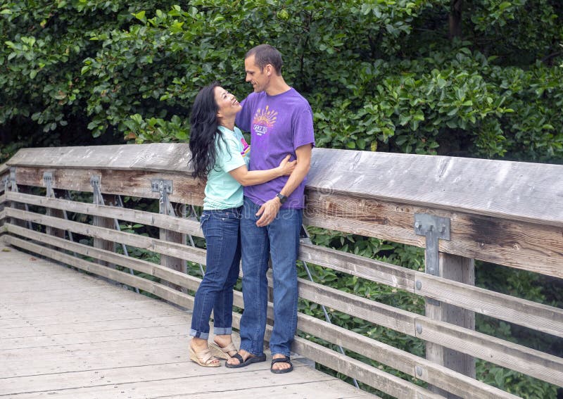 Make och fru som poserar på en träbro i Washington Park Arboretum, Seattle, Washington arkivfoto Make och fru som poserar på en träbro i Washington Park Arboretum, Seattle, Washington arkivfoto