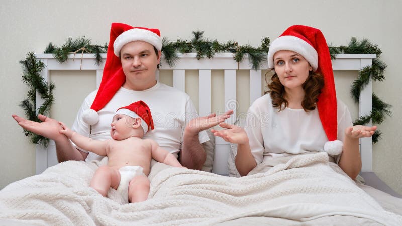 Make och maka med babyshrug i sängen dekorerad för julklappar och arkivbild
