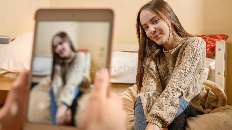 Make photographs on smartphone of beautiful smiling teenage girl at house. Modern communication, social media and