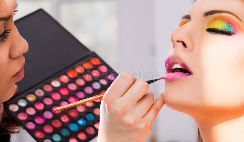 Una mujer artista el uso lápiz labial color palets sobre el mujer hermosa.