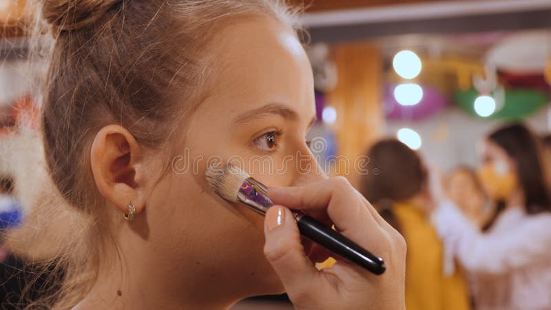 Make-up artist apply makeup on cheek with brush - closeup on model face