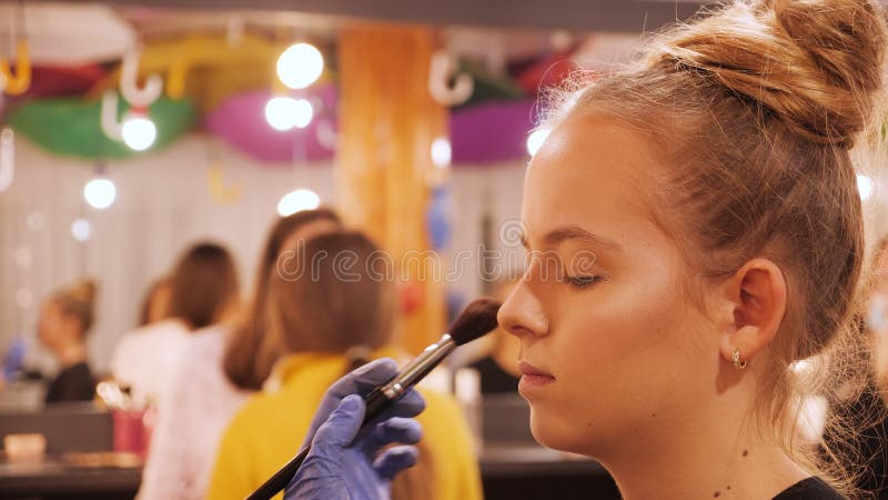 Make-up artist apply makeup on girl modelling for a class - closeup