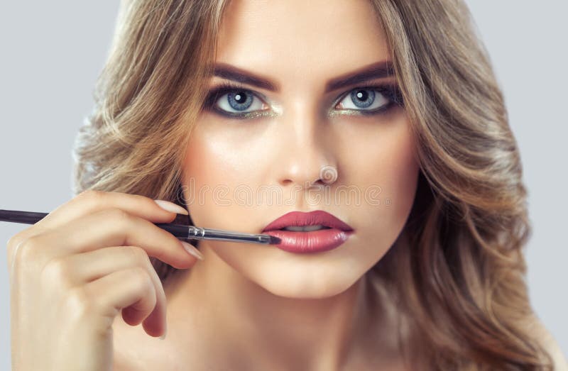 The make-up artist paints the lips of a beautiful woman, completes make-up in the beauty salon. royalty free stock photo The make-up artist paints the lips of a beautiful woman, completes make-up in the beauty salon. royalty free stock photo