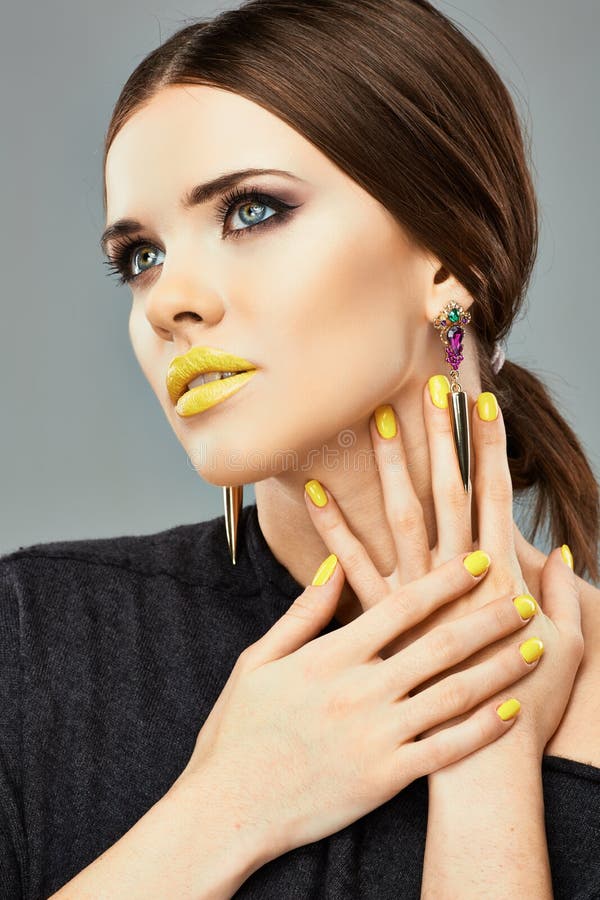 Make up. Beautiful model portrait with yellow lips and nails.