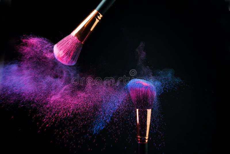 Make-up brush with colorful powder splashes explosion on black background