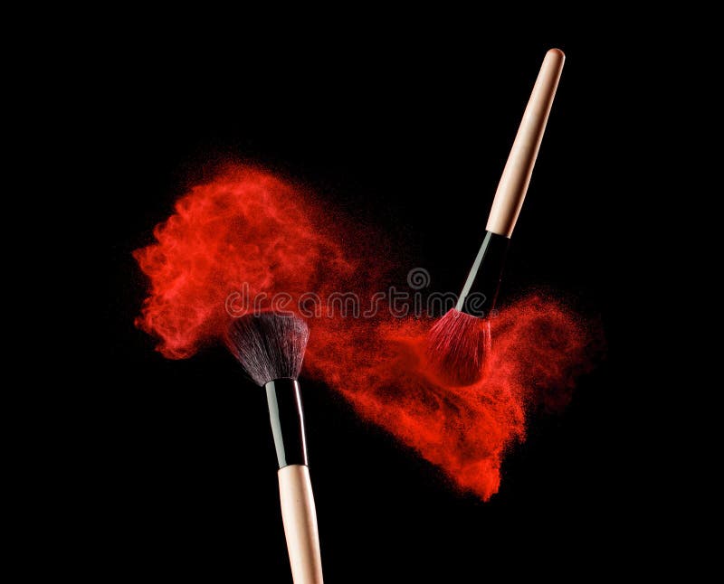 Make-up brush with powder explosion on black background