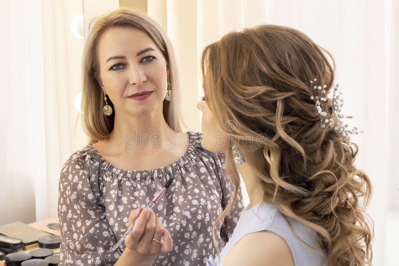 Makeup artist applies makeup to the model. lip paint brush for lipstick. beautiful girl model, portrait. Nude colors in makeup. we stock photo Makeup artist applies makeup to the model. lip paint brush for lipstick. beautiful girl model, portrait. Nude colors in makeup. we stock photo
