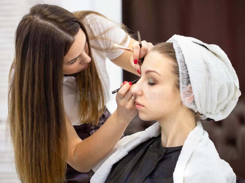 Makeup artist with cosmetic brushes in hands works with the face of young girl royalty free stock image Makeup artist with cosmetic brushes in hands works with the face of young girl royalty free stock image