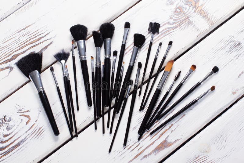 Makeup brushes on a white wooden board.