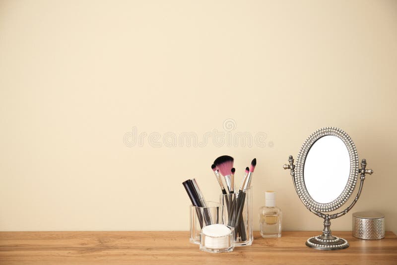 Makeup cosmetic products and tools in organizer on dressing table near color wall