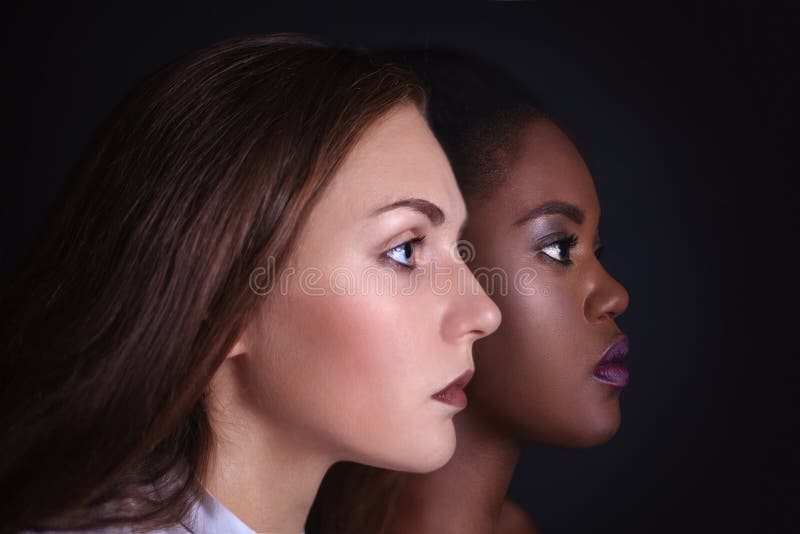 Makeup. Double female portrait. Caucasian and afro-american women posing in studio over black background