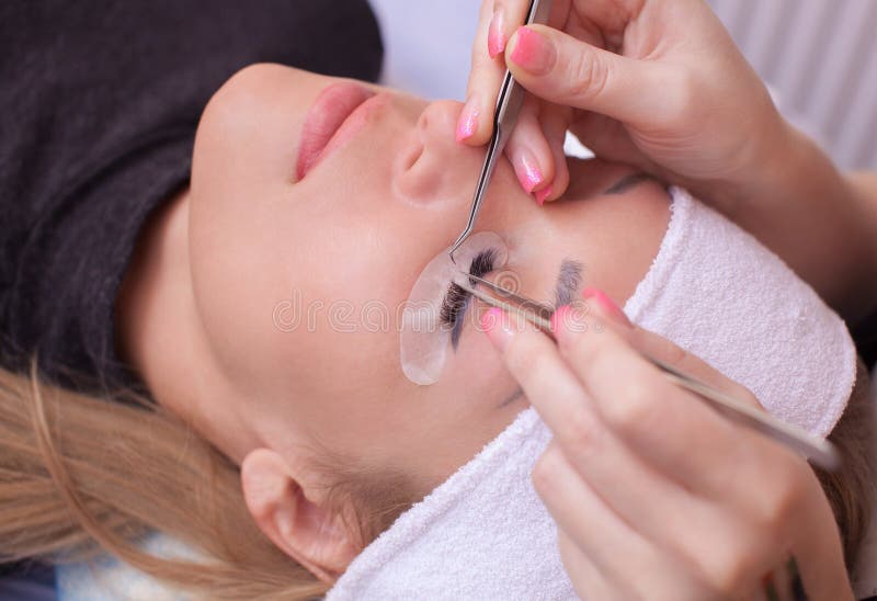 Makeup mistrz koryguje rzęsa promienie i umacnia, trzyma out parę pincety obraz royalty free Makeup mistrz koryguje rzęsa promienie i umacnia, trzyma out parę pincety obraz royalty free