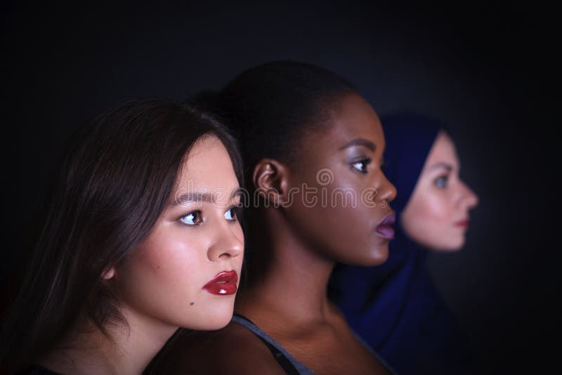 Makeup. Three women portrait. Arabic, asian and afro-american women posing in studio over black background stock photography Makeup. Three women portrait. Arabic, asian and afro-american women posing in studio over black background stock photography