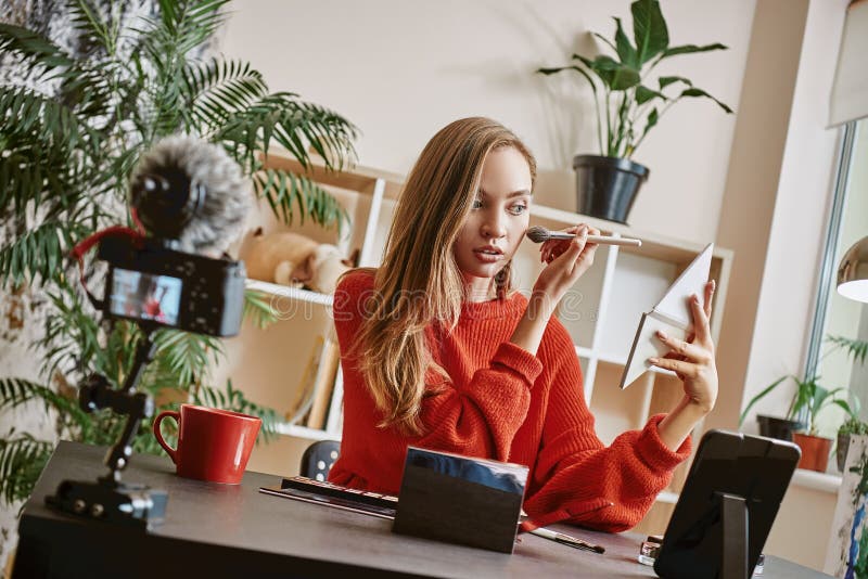 Makeup tutorial. Cute and young blogger using brush to apply highlighter while broadcasting live video to social network royalty free stock photos Makeup tutorial. Cute and young blogger using brush to apply highlighter while broadcasting live video to social network royalty free stock photos
