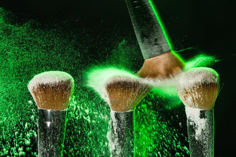 Makeupborste med grön mineralisk pulverexplosion på svart bakgrund arkivbild