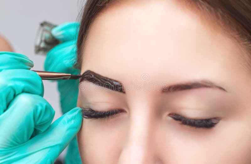 Makeupkonstnären applicerar målarfärghenna på ögonbryn i en skönhetsalong royaltyfri foto Makeupkonstnären applicerar målarfärghenna på ögonbryn i en skönhetsalong royaltyfri foto