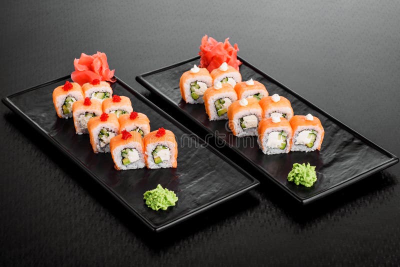 Maki Sushi ajustou-se no fundo escuro do teste padrão O nigiri, os rolos e o sashimi do grupo do sushi serviram na placa quadrada imagens de stock Maki Sushi ajustou-se no fundo escuro do teste padrão O nigiri, os rolos e o sashimi do grupo do sushi serviram na placa quadrada imagens de stock