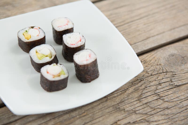 Maki sushi served on plate against wooden background