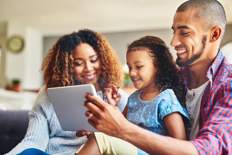 Making family time learning time. an adorable little girl and her parents using a digital tablet together on the sofa at stock image