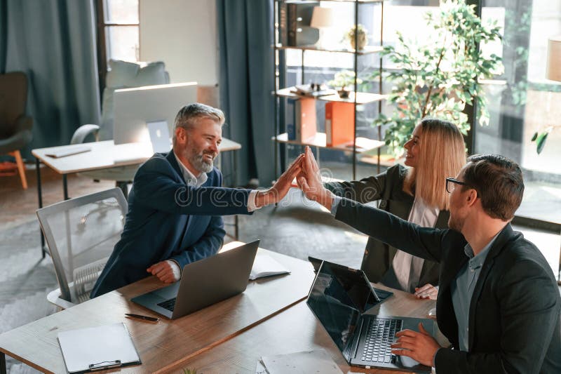 Making High Five, Sitting by the Table. Group of Business People are