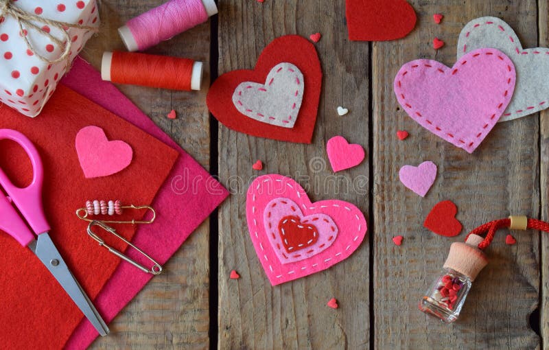 Making pink and red hearts of felt with your own hands. Valentine`s Day background. Valentine gift making, diy hobby. Children`s stock photo Making pink and red hearts of felt with your own hands. Valentine`s Day background. Valentine gift making, diy hobby. Children`s stock photo