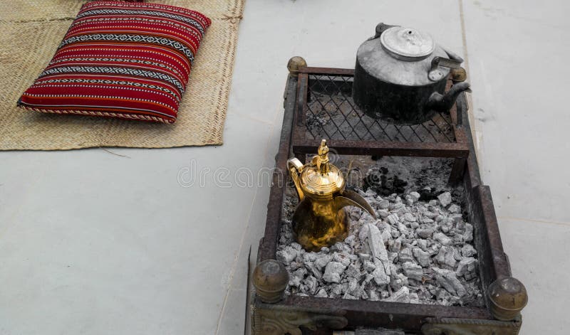 Making traditional Arabian coffee - golden Arabic and Middle Eastern coffee pot Dallah on top of charcoal around Arabic decorati stock image Making traditional Arabian coffee - golden Arabic and Middle Eastern coffee pot Dallah on top of charcoal around Arabic decorati stock image