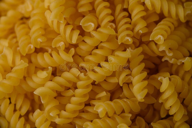 Makro widok suchego makaronu fusilli wypełniającego ramę. Tekstura spiralna idealna do opakowań lub wizualizacji gotowania żywnośc. Suchy makaron Fusilli Pełne Tło Ramki